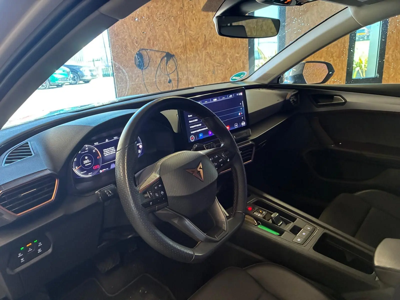 Vue intérieure côté conducteur de la CUPRA LEON ST 2024 avec tableau de bord numérique et volant multifonction noir.
