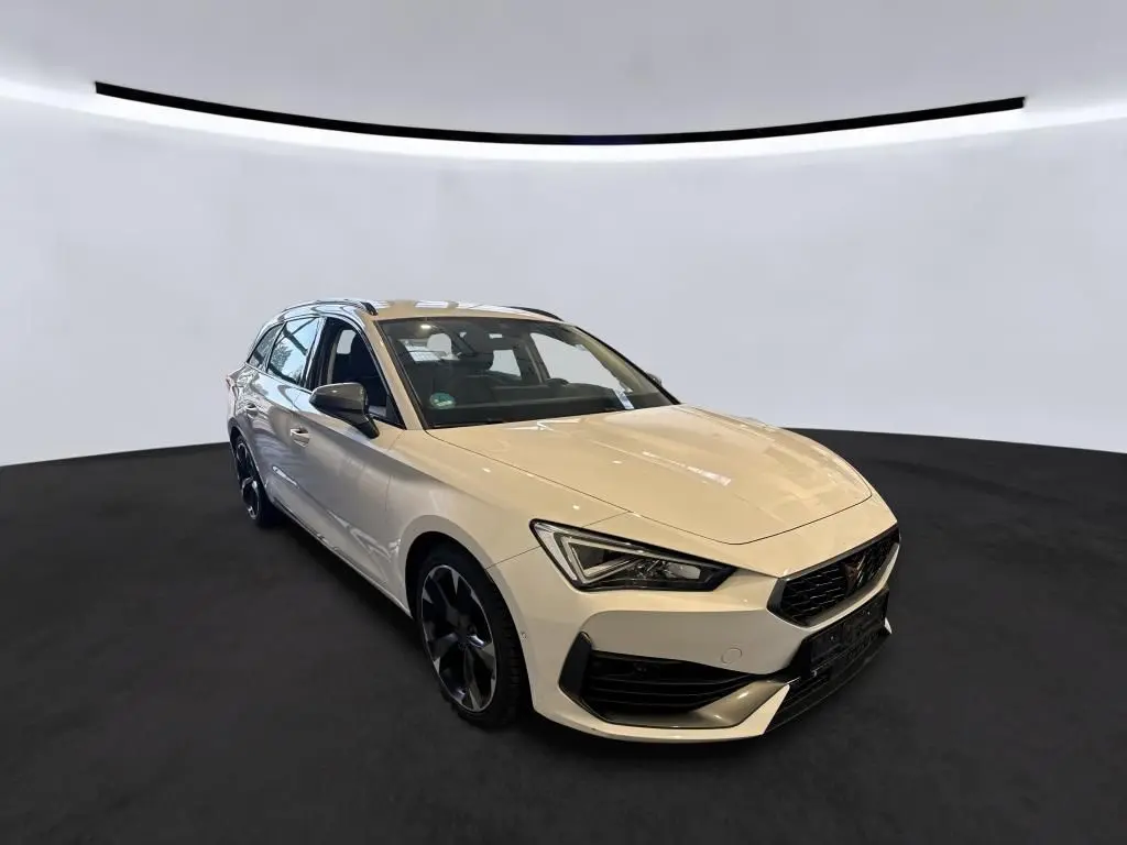 Vue 3/4 avant droite d'une CUPRA Leon ST blanche 2024 avec jantes noires et calandre distinctive.