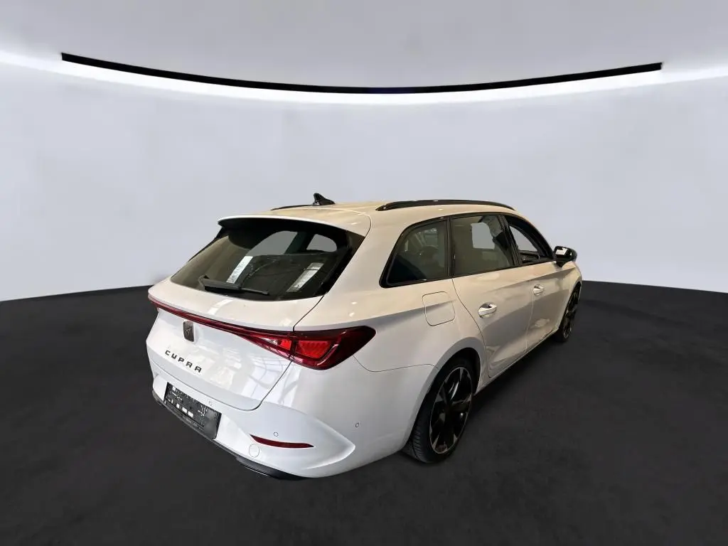 Vue 3/4 arrière droite d'une CUPRA Leon ST blanche 2024 avec toit panoramique et feux arrière LED reliés.