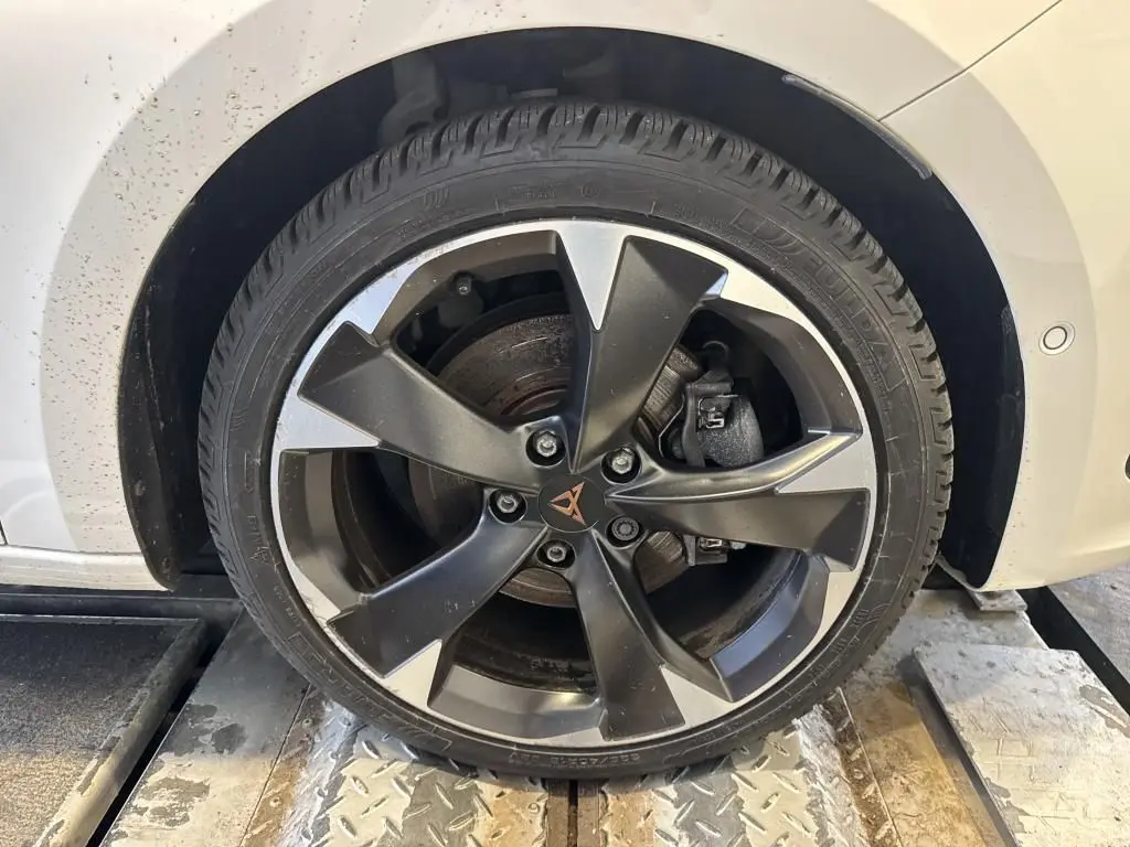 Gros plan sur la roue avant droite d'une CUPRA LEON ST blanche 2024, avec jante alliage noire et argentée au design sportif.