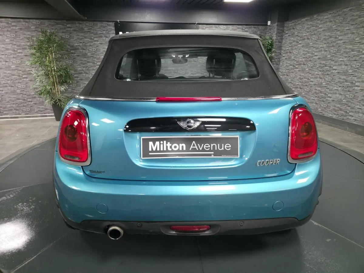 Vue arrière d'une MINI Cabriolet bleu avec capote noire et sortie d'échappement chromée à droite.