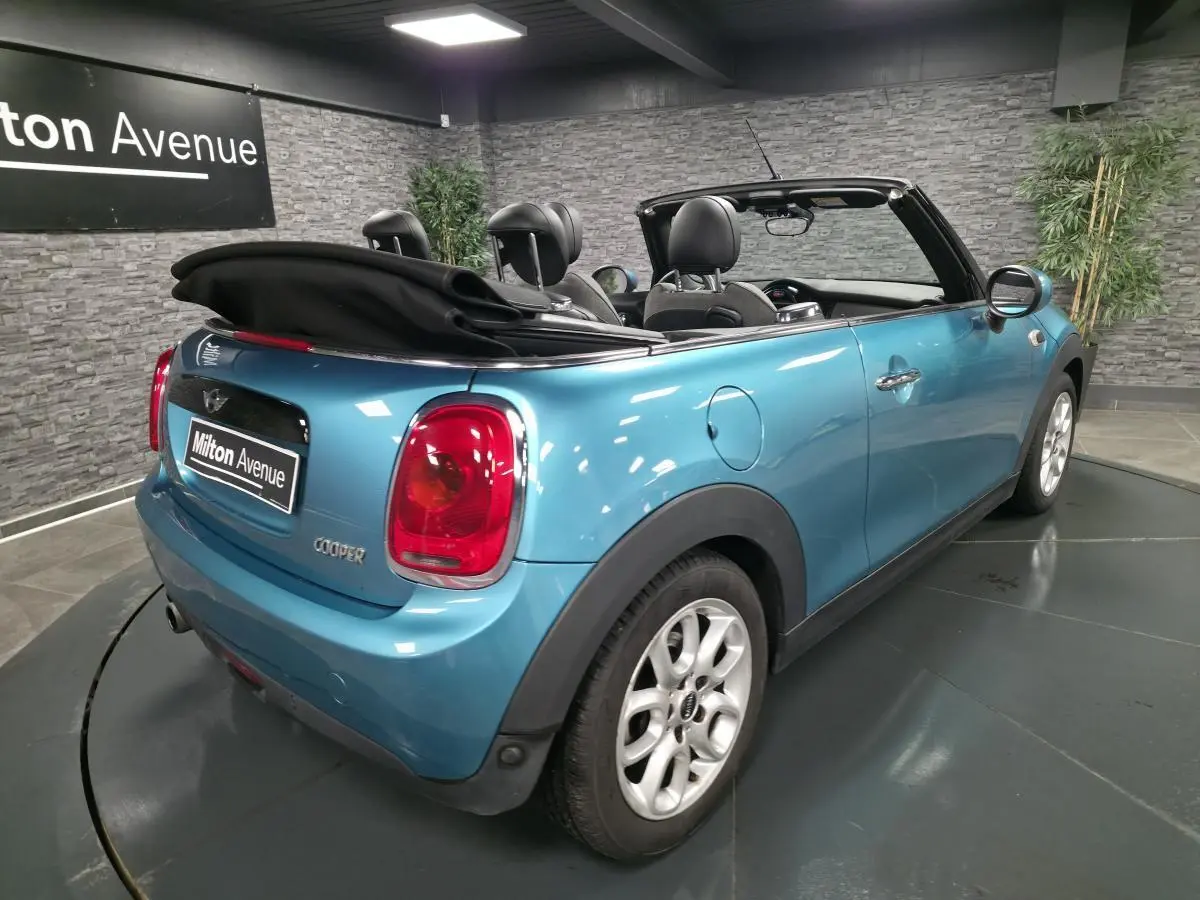 MINI Cabriolet bleu vue 3/4 arrière droit avec capote noire repliée et jantes argentées.