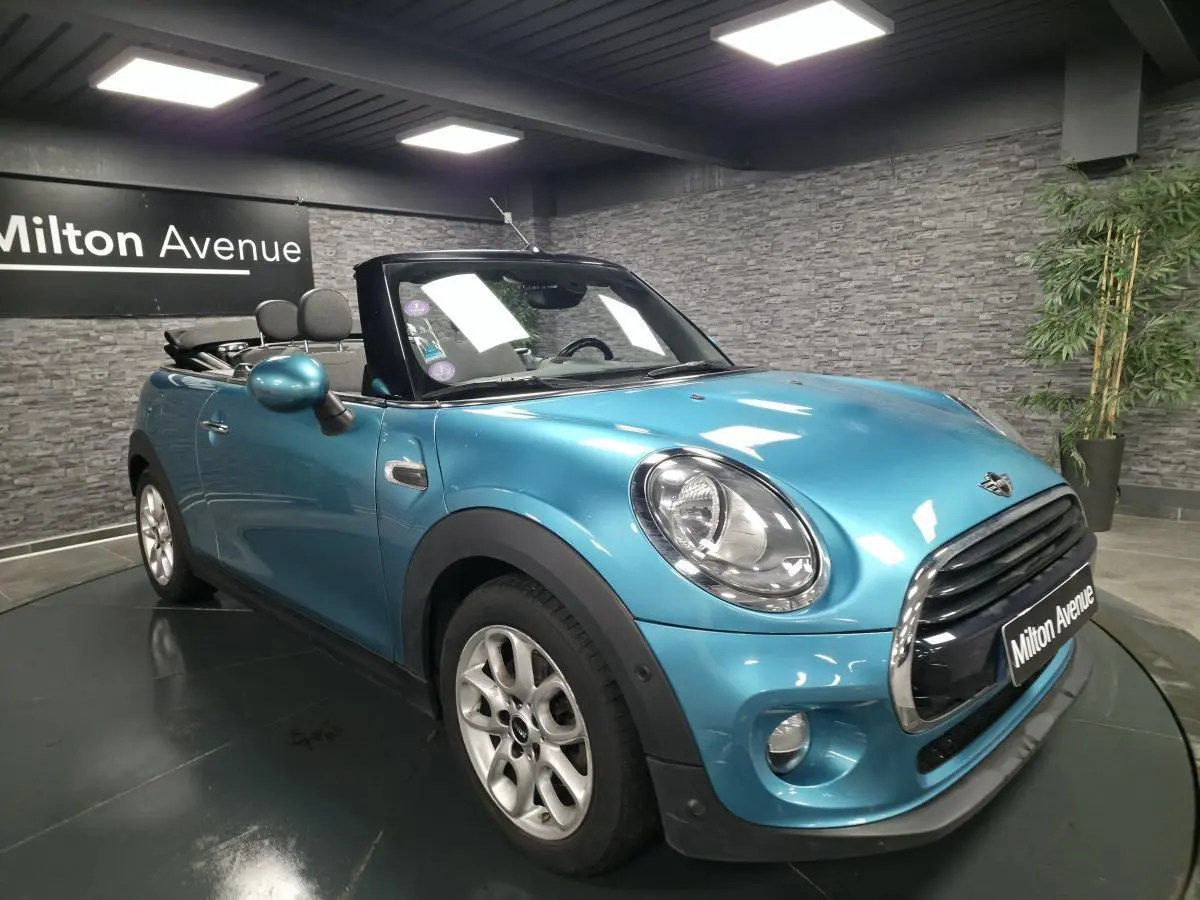 MINI Cabriolet bleu vue 3/4 avant droit, capote noire ouverte et jantes argentées visibles.