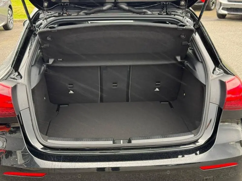Coffre ouvert vu de l'arrière d'une Mercedes Classe A 200 d AMG Line noir brillant avec banquette rabattable.