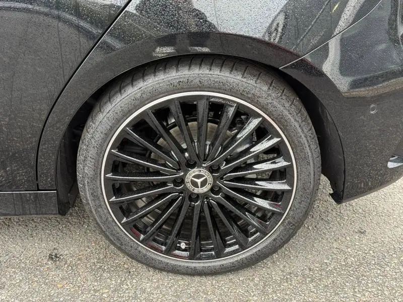 Gros plan sur la roue arrière droite d’une Mercedes Classe A 200 d AMG Line gris montagne métallisé avec jante alu noire multi-branches.