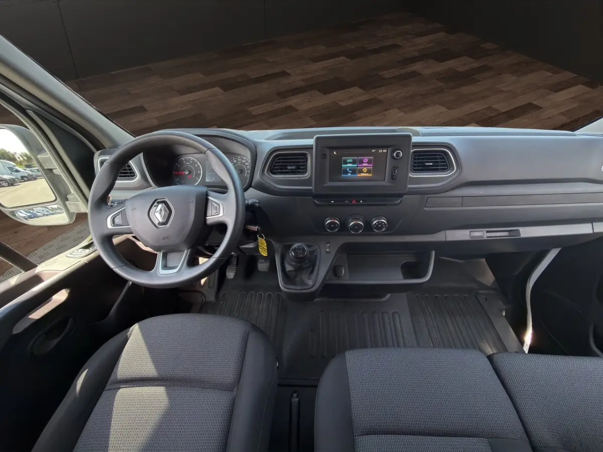 Vue intérieure avant du tableau de bord du Renault Master 2023 avec volant, écran tactile central et sièges gris.
