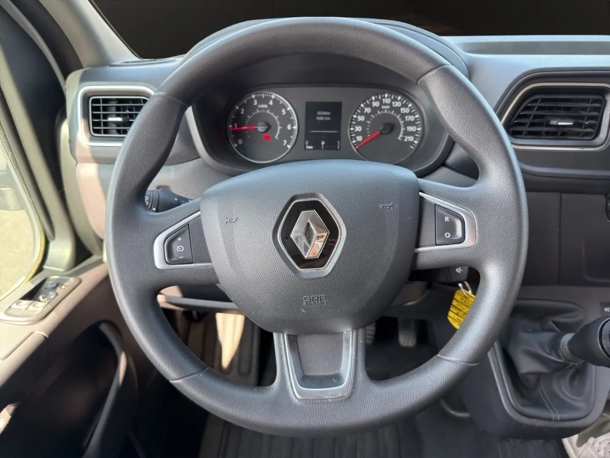 Vue rapprochée du volant noir Renault Master 2023 avec tableau de bord et commandes visibles en arrière-plan.