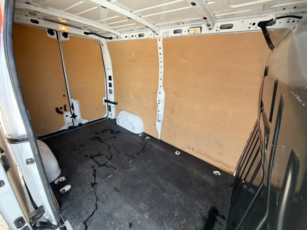 Vue intérieure arrière droite du Renault Master blanc 2023 avec cloison bois et sol noir antidérapant.