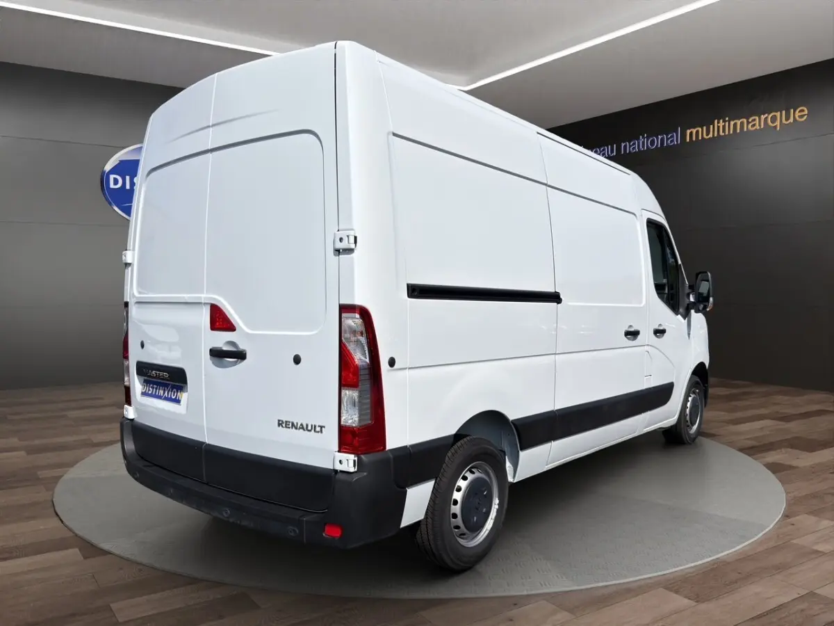 Renault Master blanc en vue 3/4 arrière droit, fourgon utilitaire avec panneaux latéraux lisses et feux arrière verticaux.