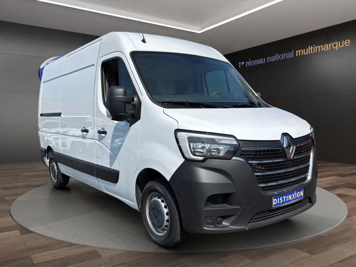 Renault Master blanc en vue 3/4 avant droit, avec calandre noire et jantes acier, sur fond intérieur showroom.