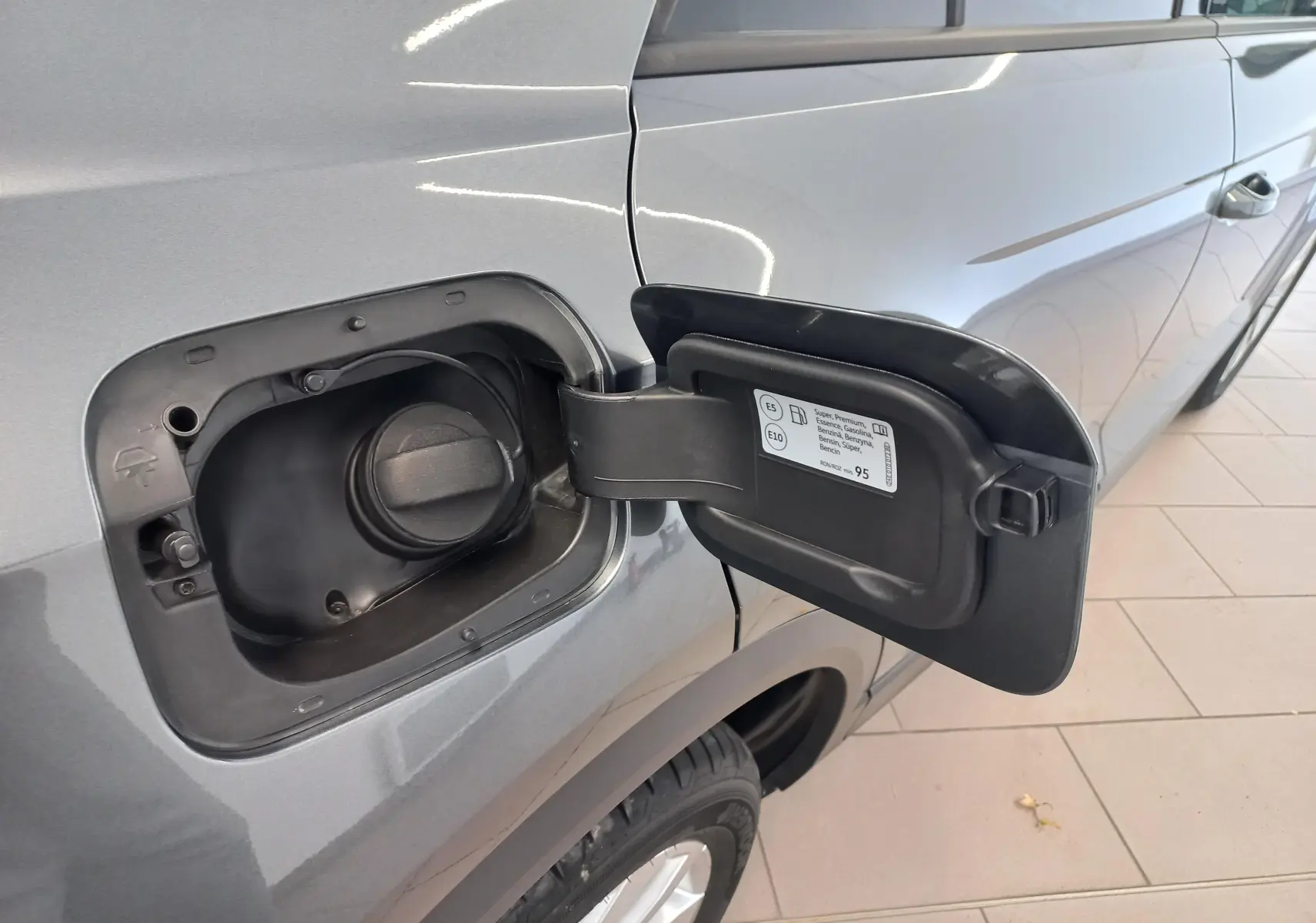 Vue rapprochée de la trappe à carburant ouverte côté gauche du Volkswagen T-Roc gris Indium 2025.