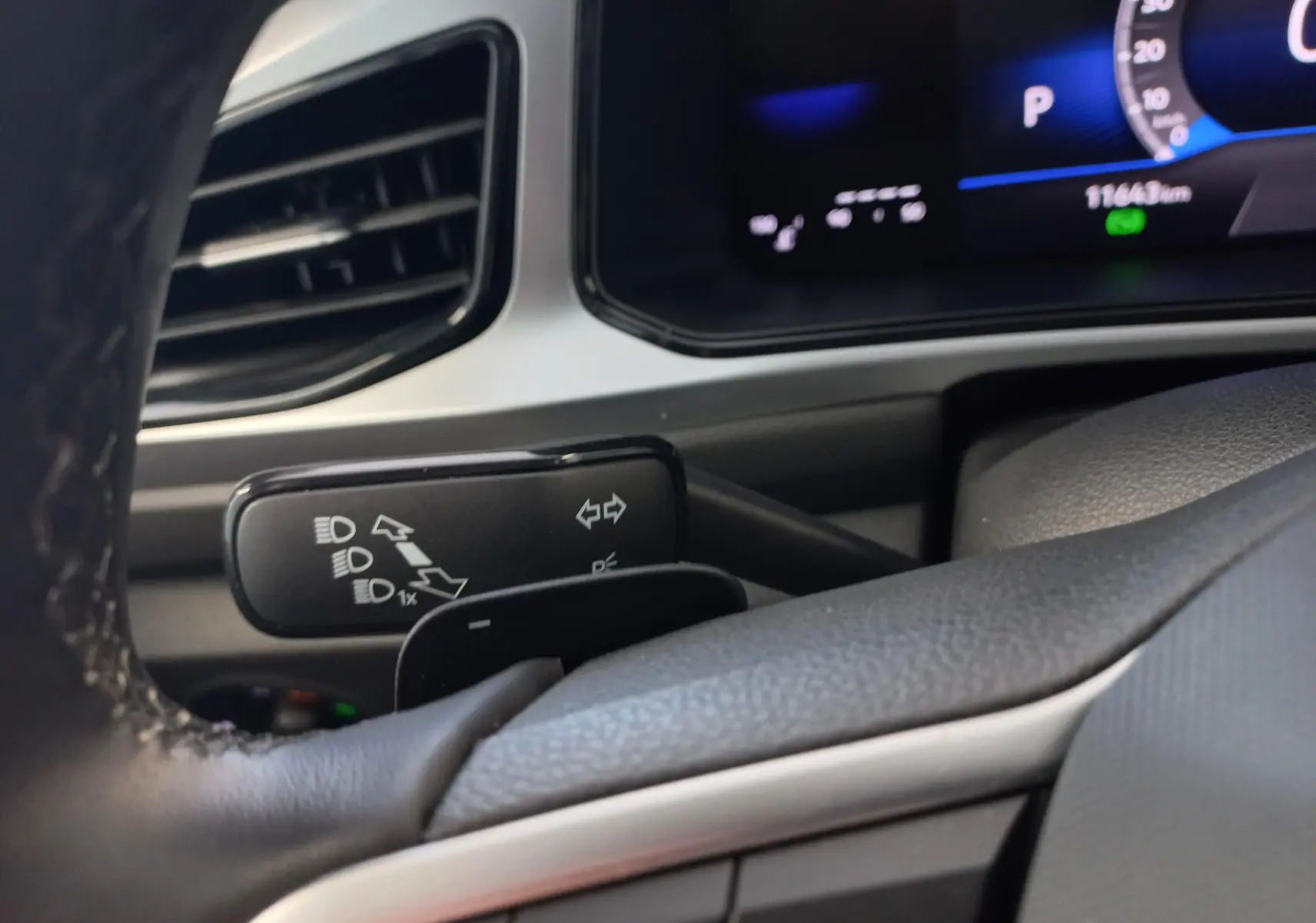 Gros plan sur la manette de clignotants à gauche du volant du Volkswagen T-Roc 2025, intérieur gris et tableau de bord numérique.