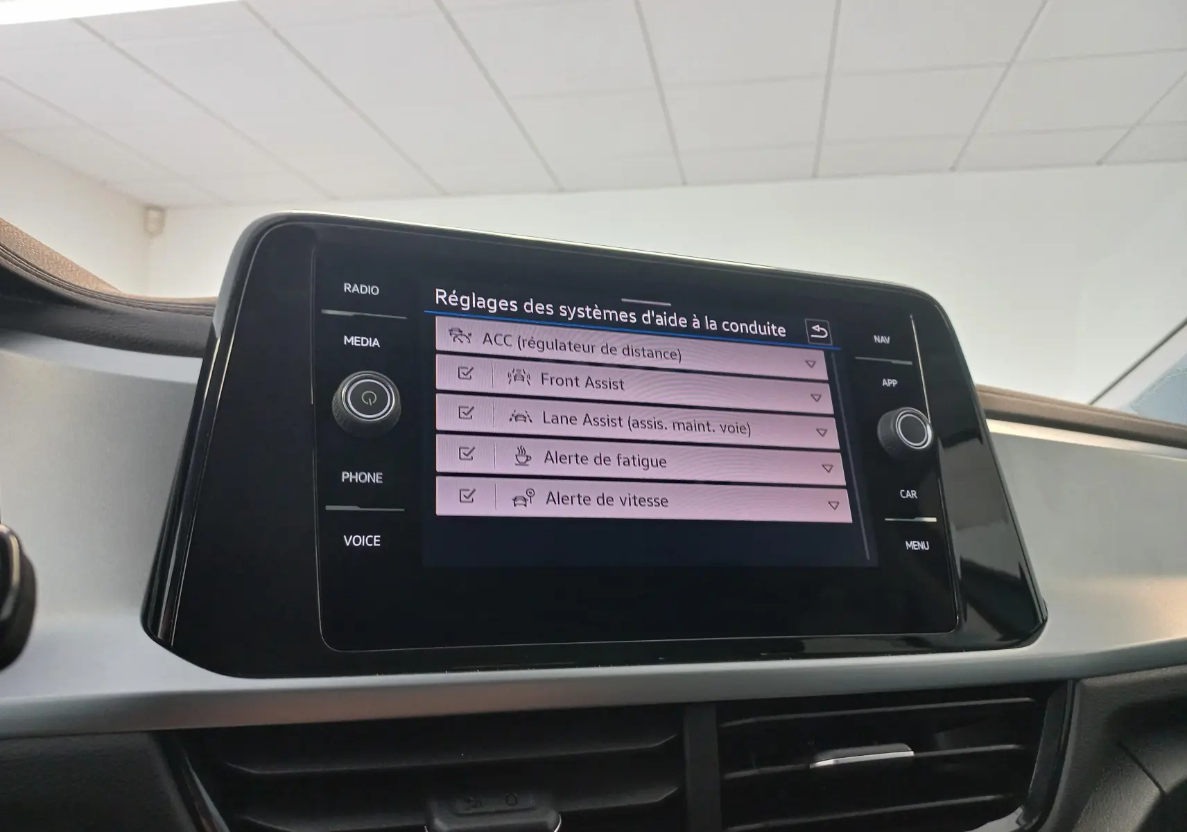 Écran tactile central du Volkswagen T-Roc 2025 gris Indium, affichant les réglages des aides à la conduite.