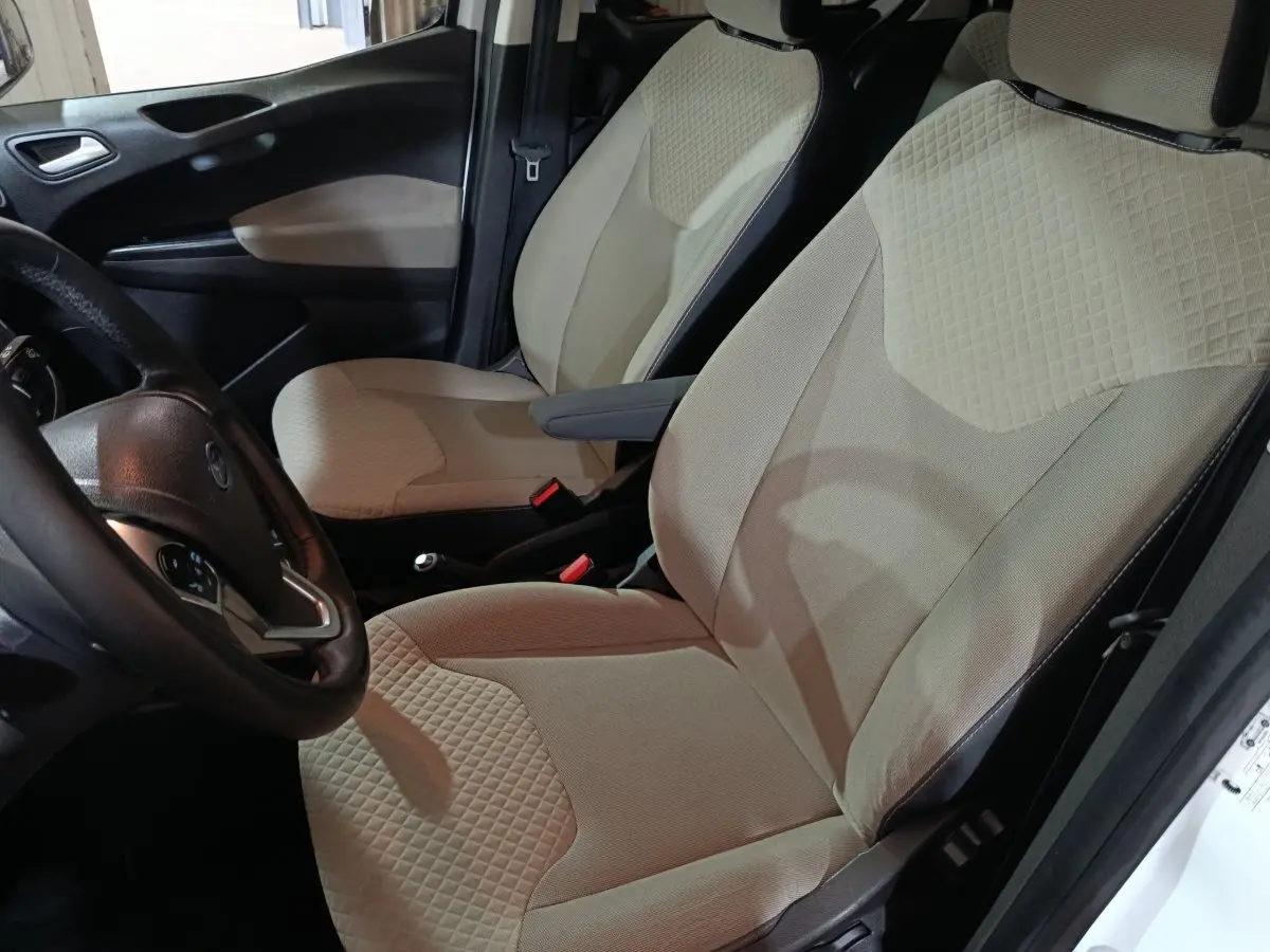 Vue intérieure côté conducteur du Ford Grand Tourneo Connect blanc, sièges avant beige avec texture matelassée.