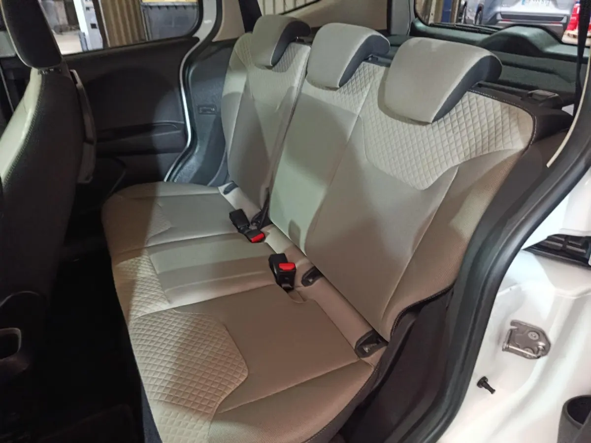 Vue intérieure côté droit sur la banquette arrière beige du Ford Grand Tourneo Connect blanc, avec porte ouverte.