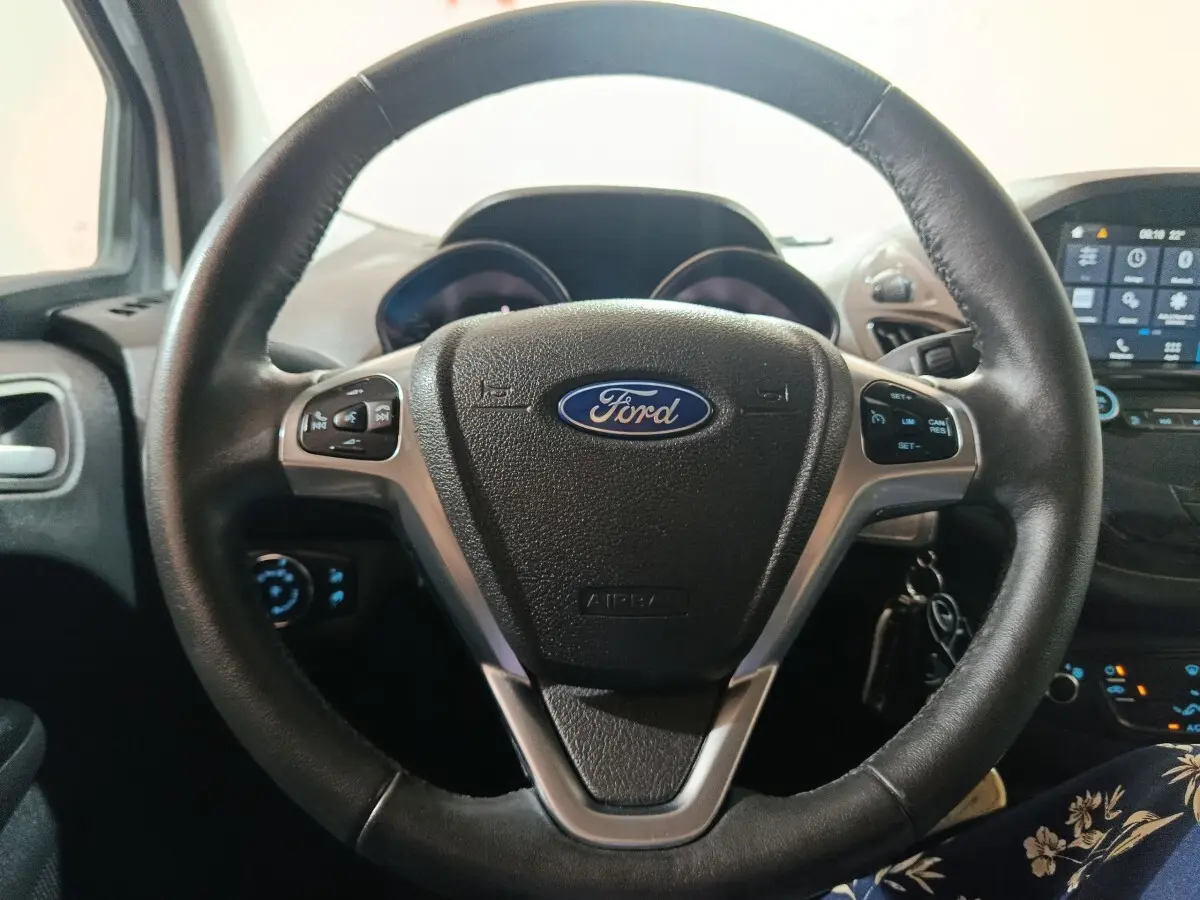 Vue rapprochée du volant cuir noir du Ford Grand Tourneo Connect 2020 avec tableau de bord et écran tactile en arrière-plan.