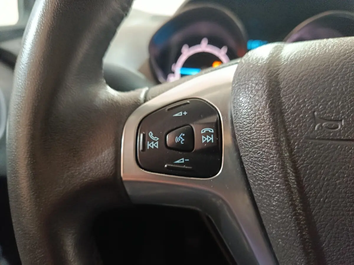 Gros plan sur les commandes vocales et téléphone du volant en cuir noir du Ford Grand Tourneo Connect blanc 2020.