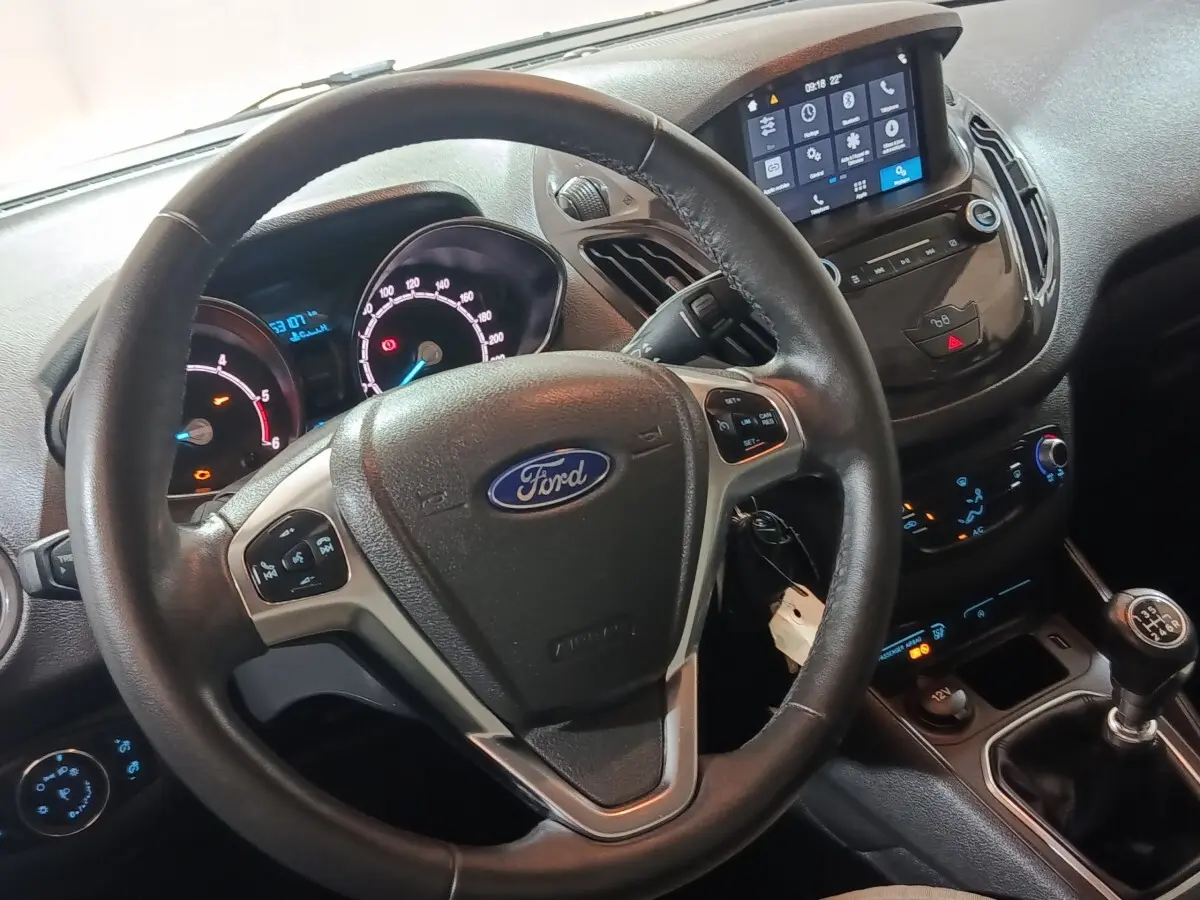 Vue intérieure centrée sur le volant cuir multifonctions et tableau de bord digital du Ford Grand Tourneo Connect blanc.