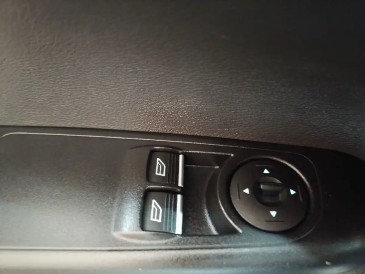 Gros plan sur les commandes de lève-vitres et réglage des rétroviseurs côté conducteur du Ford Grand Tourneo Connect blanc.