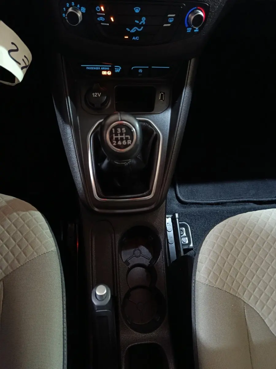 Vue plongeante sur la console centrale du Ford Grand Tourneo Connect 2020, boîte manuelle, sièges beige à motifs.