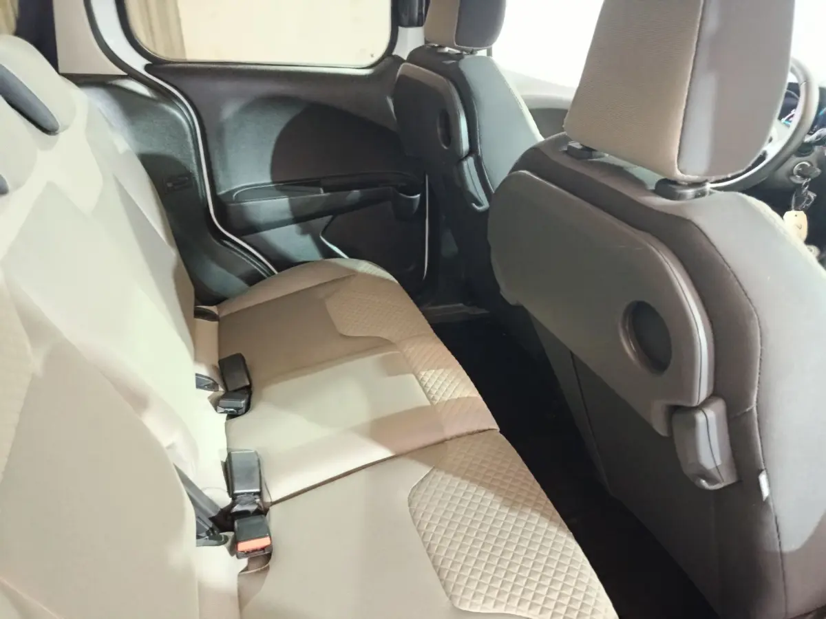 Vue intérieure côté droit sur la banquette arrière beige du Ford Grand Tourneo Connect blanc, avec dossiers avant noirs.