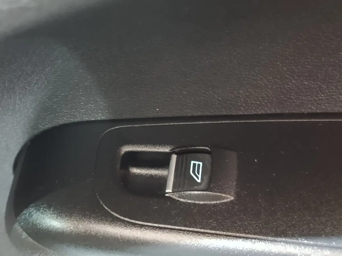 Bouton de commande électrique de lève-vitre noir sur panneau intérieur de porte d’un Ford Grand Tourneo Connect blanc.