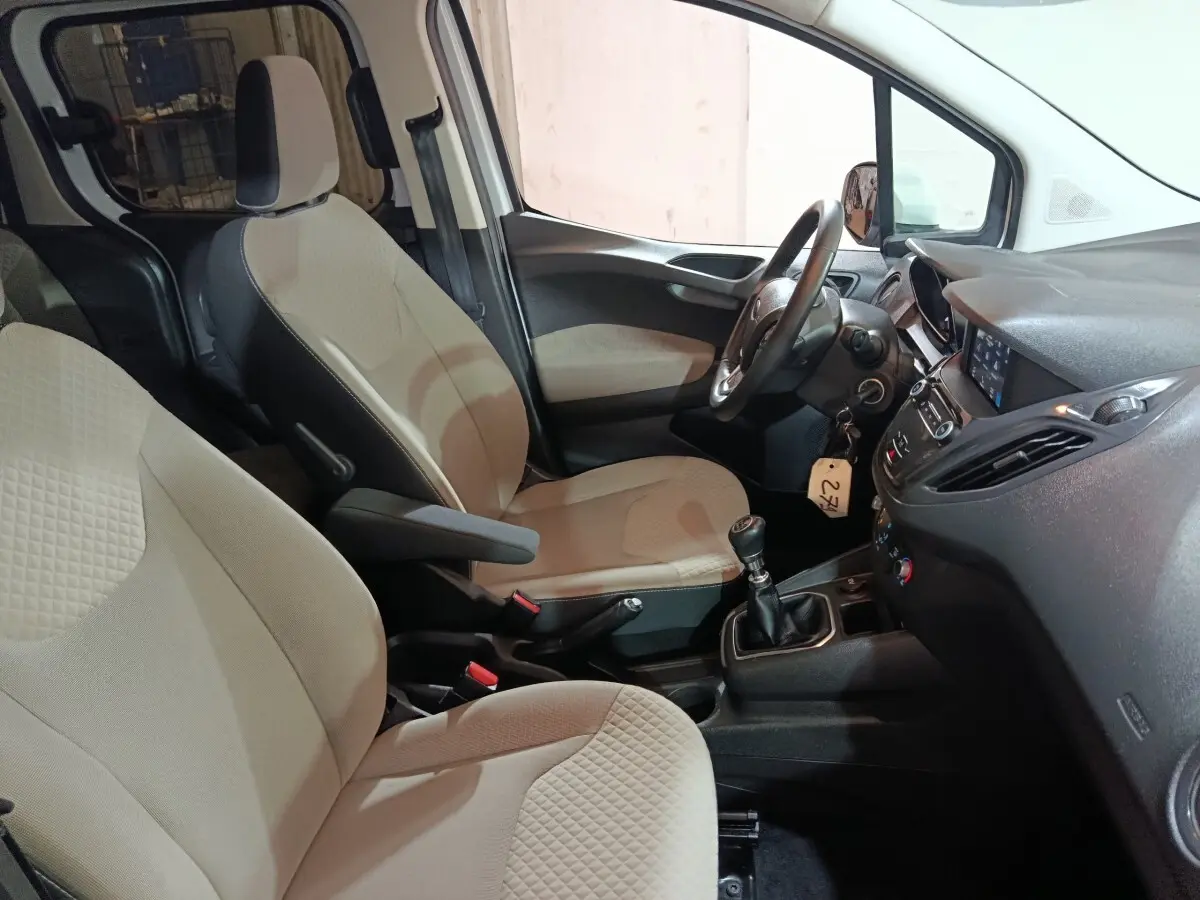 Vue intérieure côté conducteur du Ford Grand Tourneo Connect 2020, sièges beige et volant cuir avec boîte manuelle.