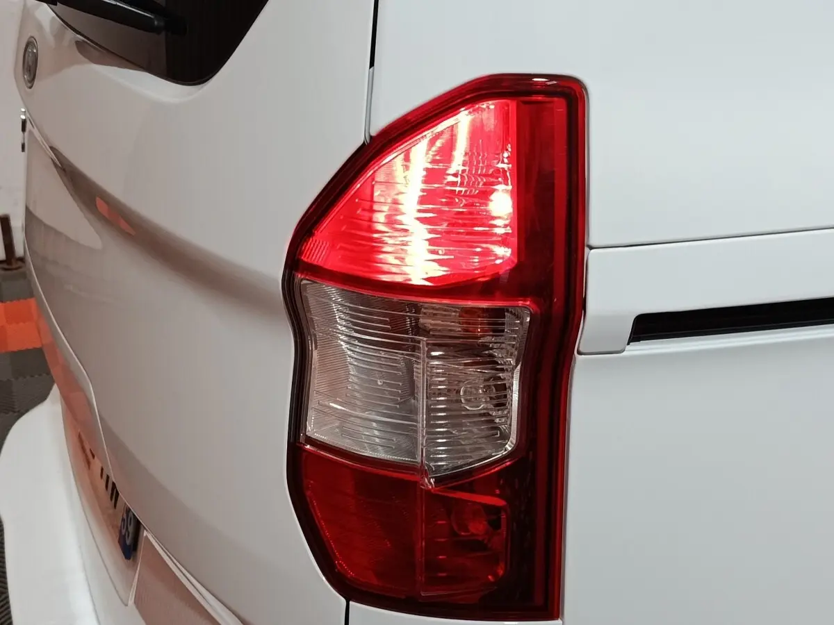 Gros plan sur le feu arrière droit d’un Ford Grand Tourneo Connect blanc, montrant les détails du feu stop et clignotant.