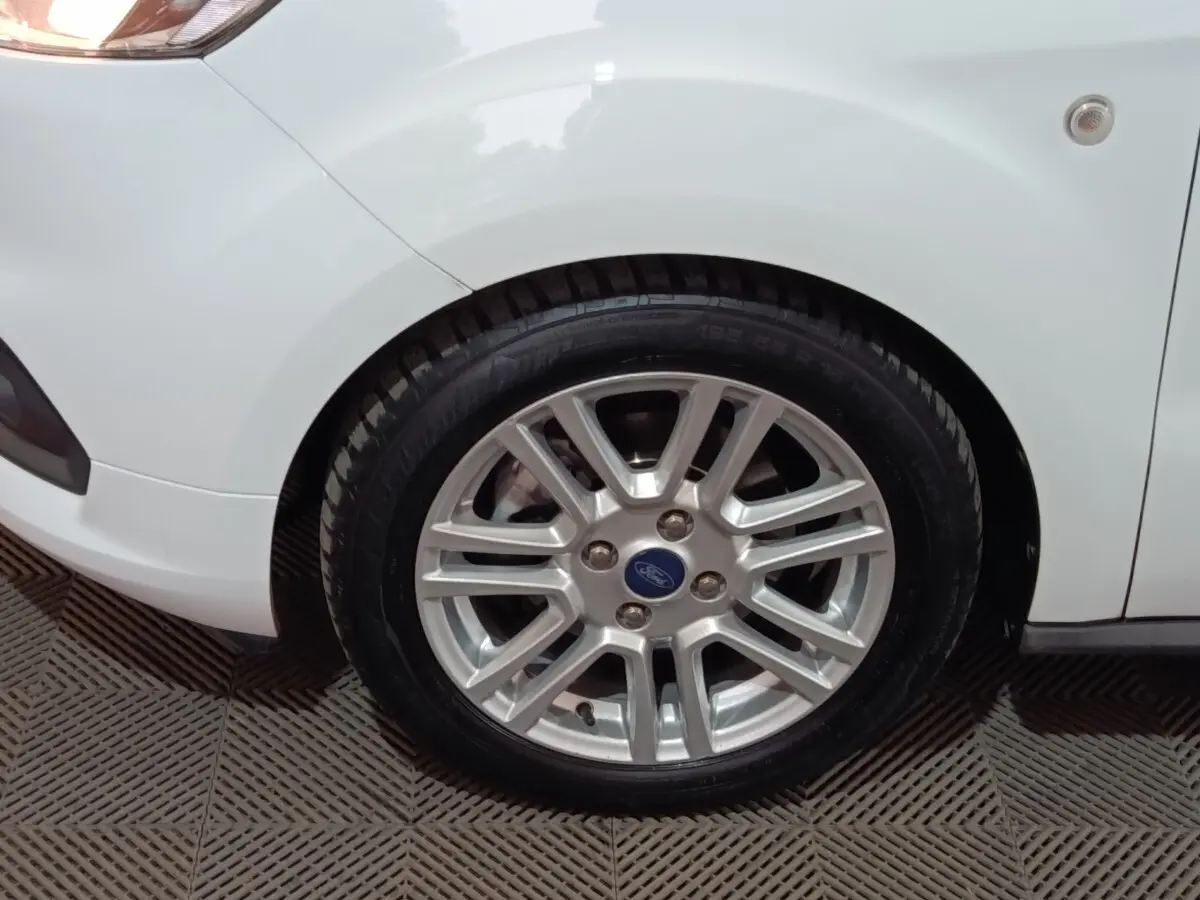 Gros plan sur la roue avant gauche argentée d’un Ford Grand Tourneo Connect blanc, avec partie de l’aile visible.