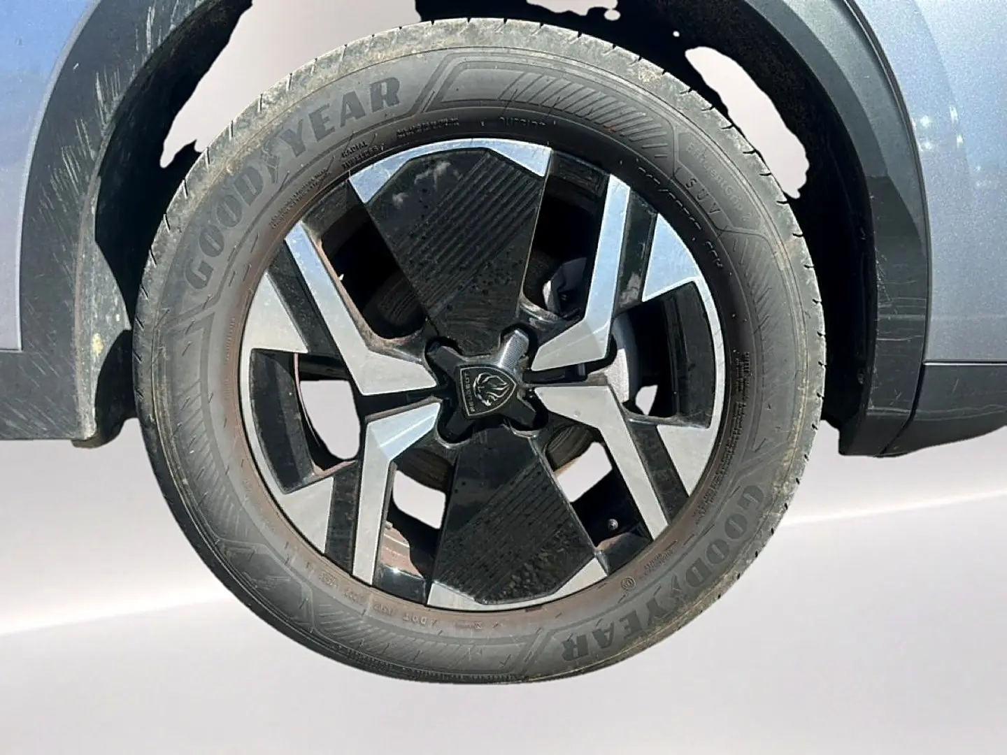 Gros plan sur la roue avant droite du Peugeot 2008 gris Artense avec jante alu bicolore et pneu Goodyear.