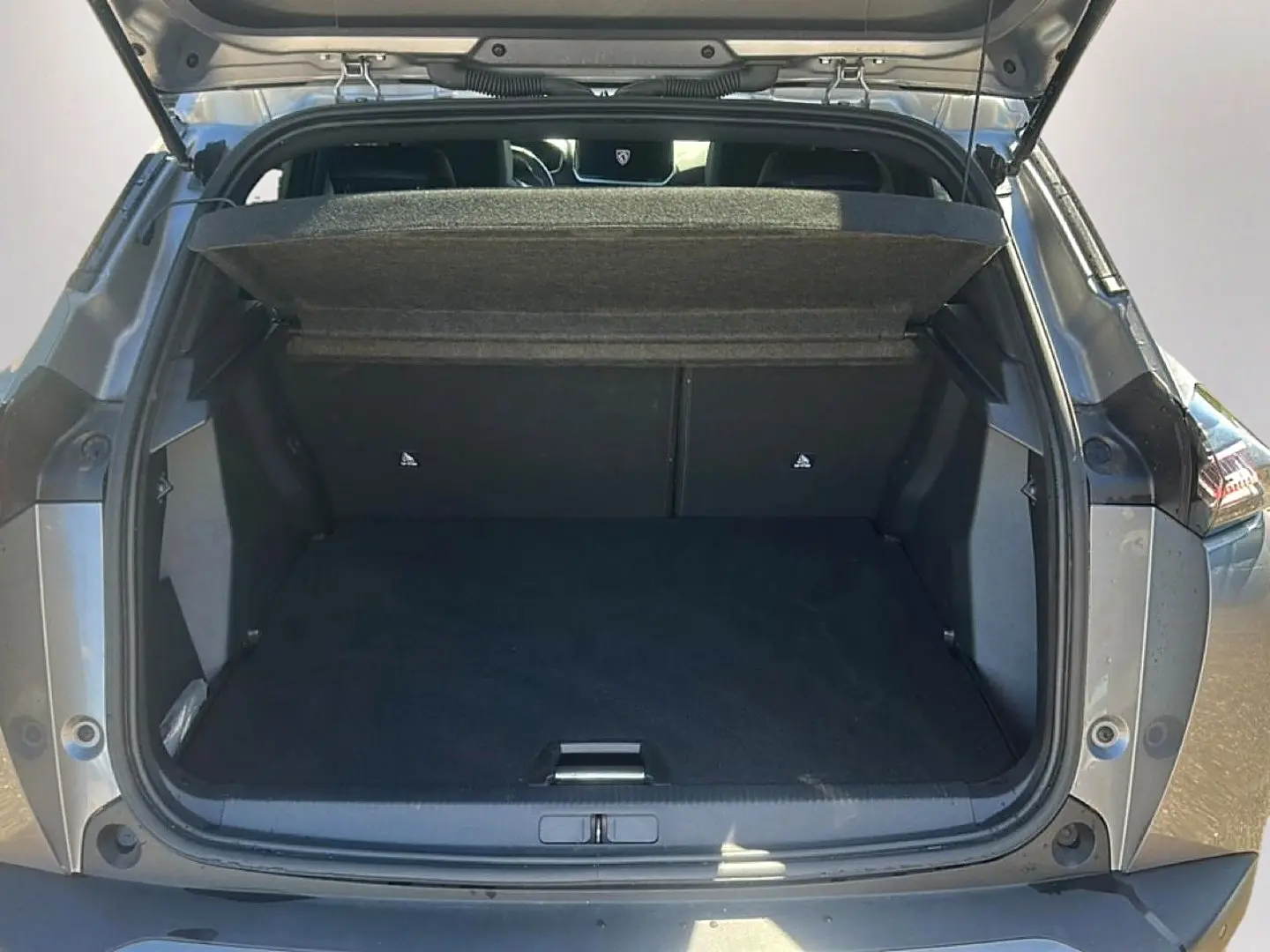 Coffre ouvert vu de l'arrière d'un Peugeot 2008 gris artense, montrant l'espace de chargement et la tablette cache-bagages.