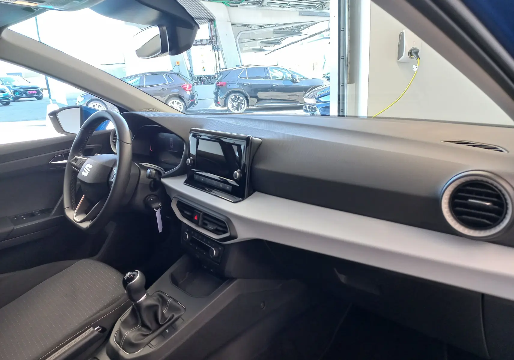 Intérieur de la SEAT Ibiza 1.0 TSI 95 Copa 2025 en bleu saphir, vue côté conducteur sur tableau de bord et levier de vitesses manuel.