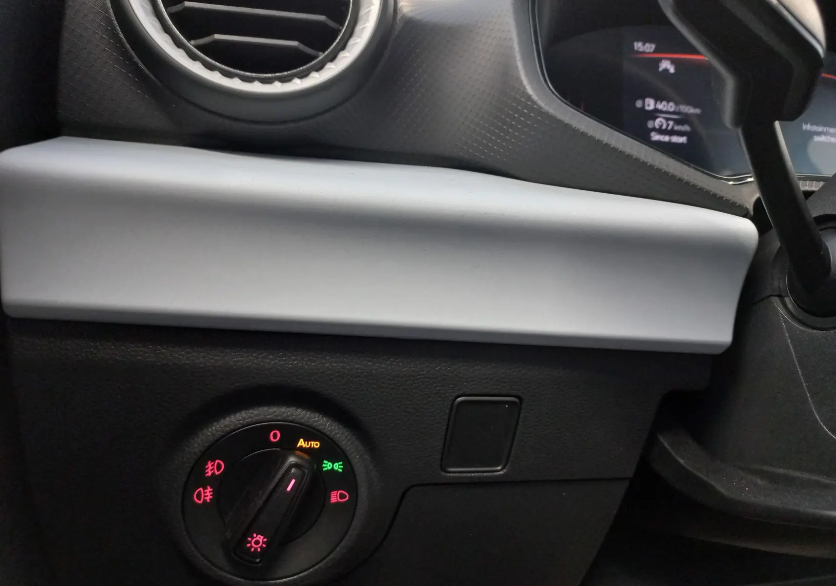 Détail intérieur du tableau de bord côté gauche de la SEAT Ibiza bleu saphir, avec commande des phares et aérateur rond.