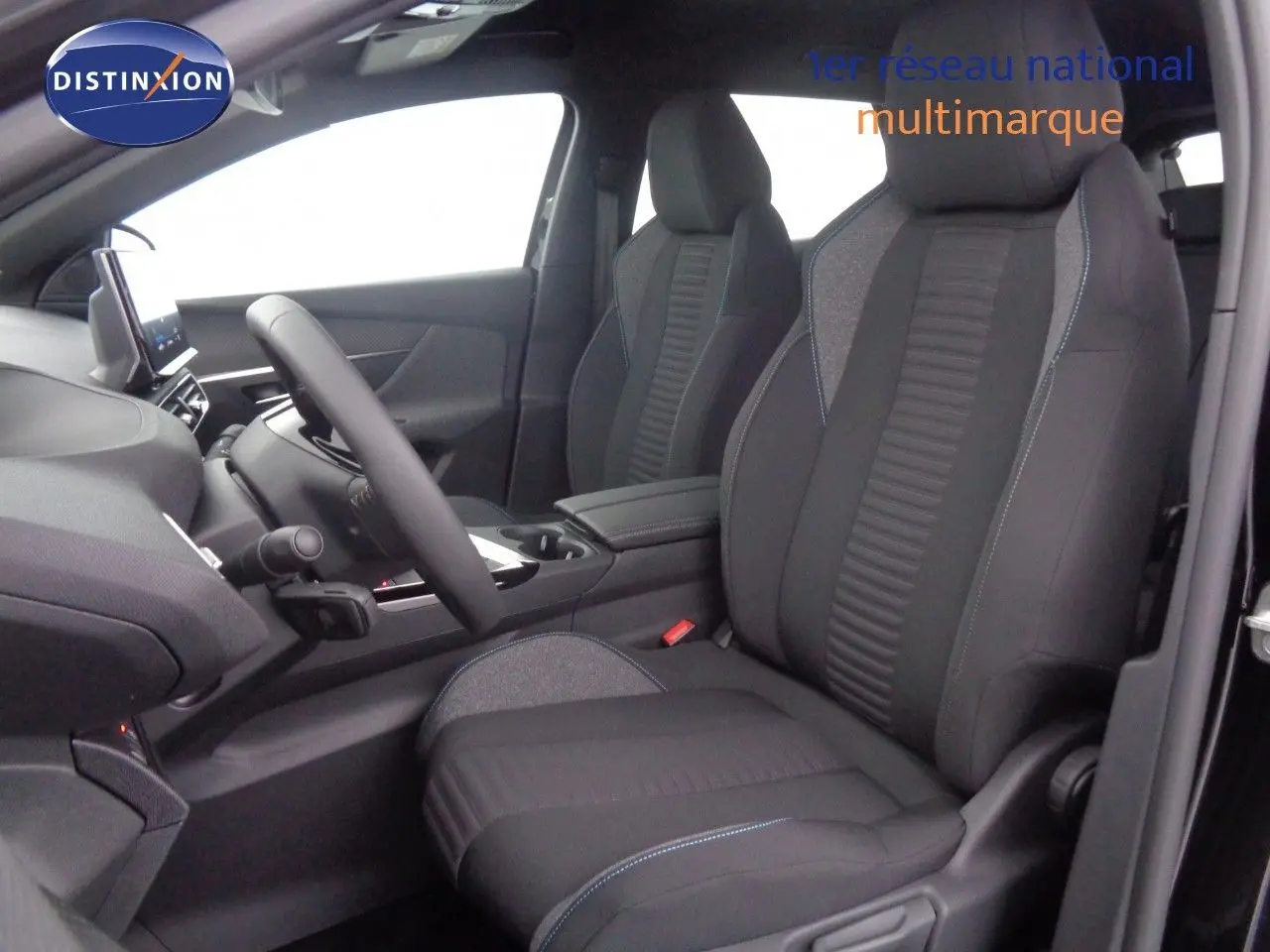 Vue intérieure côté conducteur du Peugeot 3008 2023 avec sièges tissu gris noir et surpiqûres bleues, volant et console centrale visibles.
