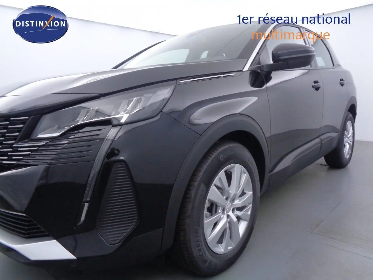 Gros plan sur la roue avant gauche d'un Peugeot 3008 noir perle métal avec jante alu et partie avant visible.