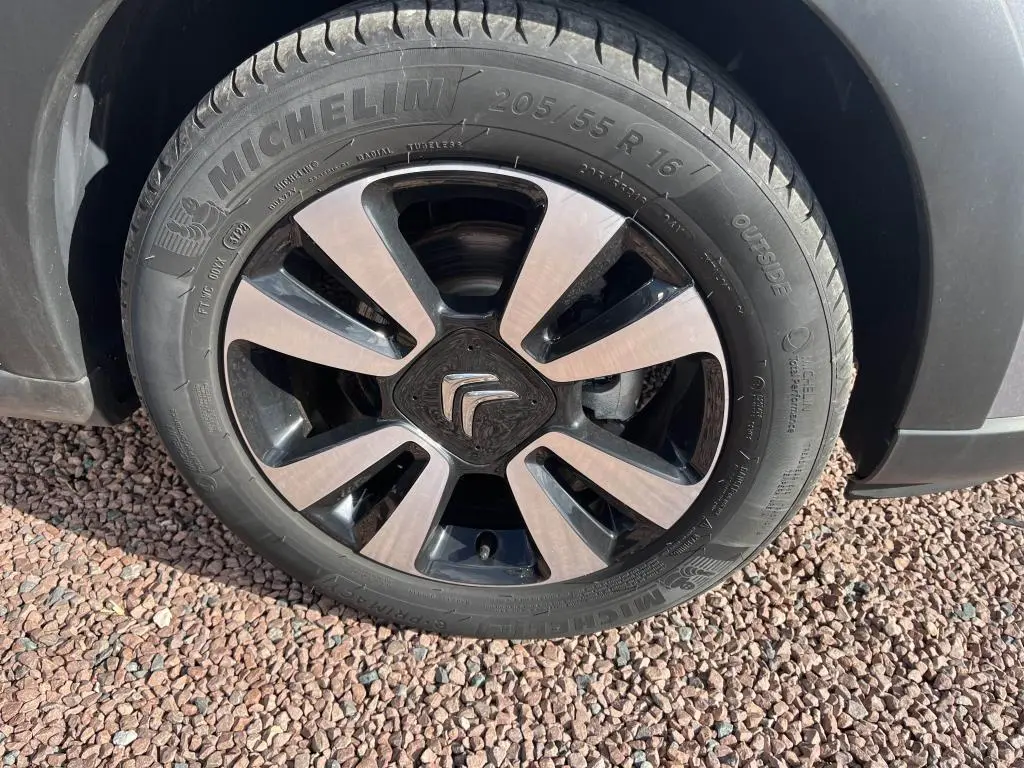 Gros plan sur la roue avant gauche d'une Citroën C3 gris avec jante alliage bicolore et pneu Michelin.