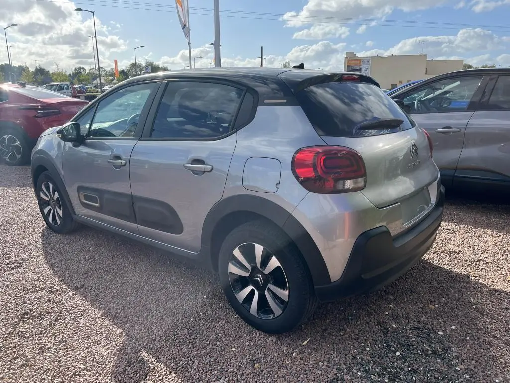 Vue 3/4 arrière droite d'une Citroën C3 gris nacré avec toit noir et protections latérales noires.