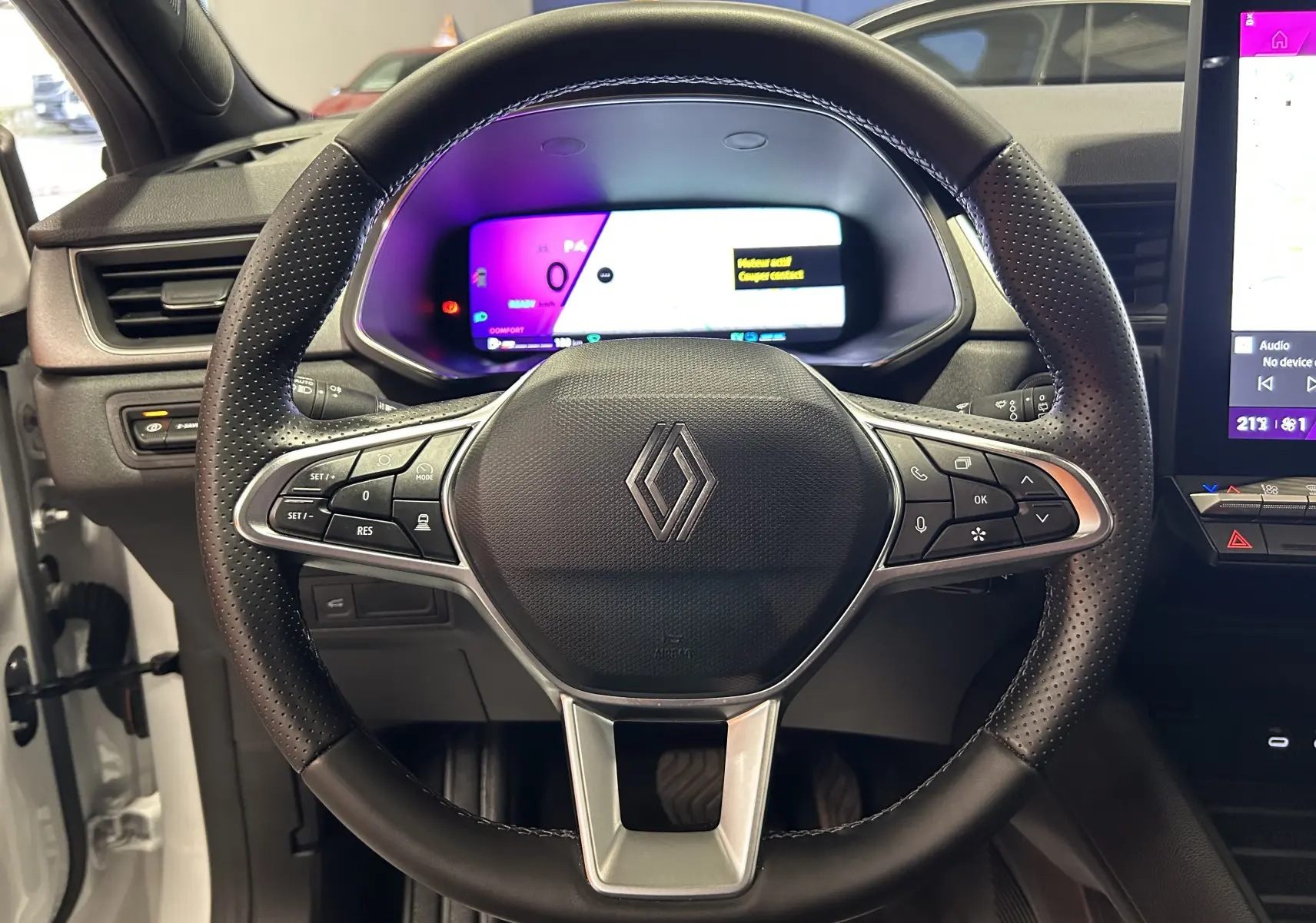Vue rapprochée du volant en cuir perforé du Renault Symbioz blanc nacré avec tableau de bord numérique et écran tactile.