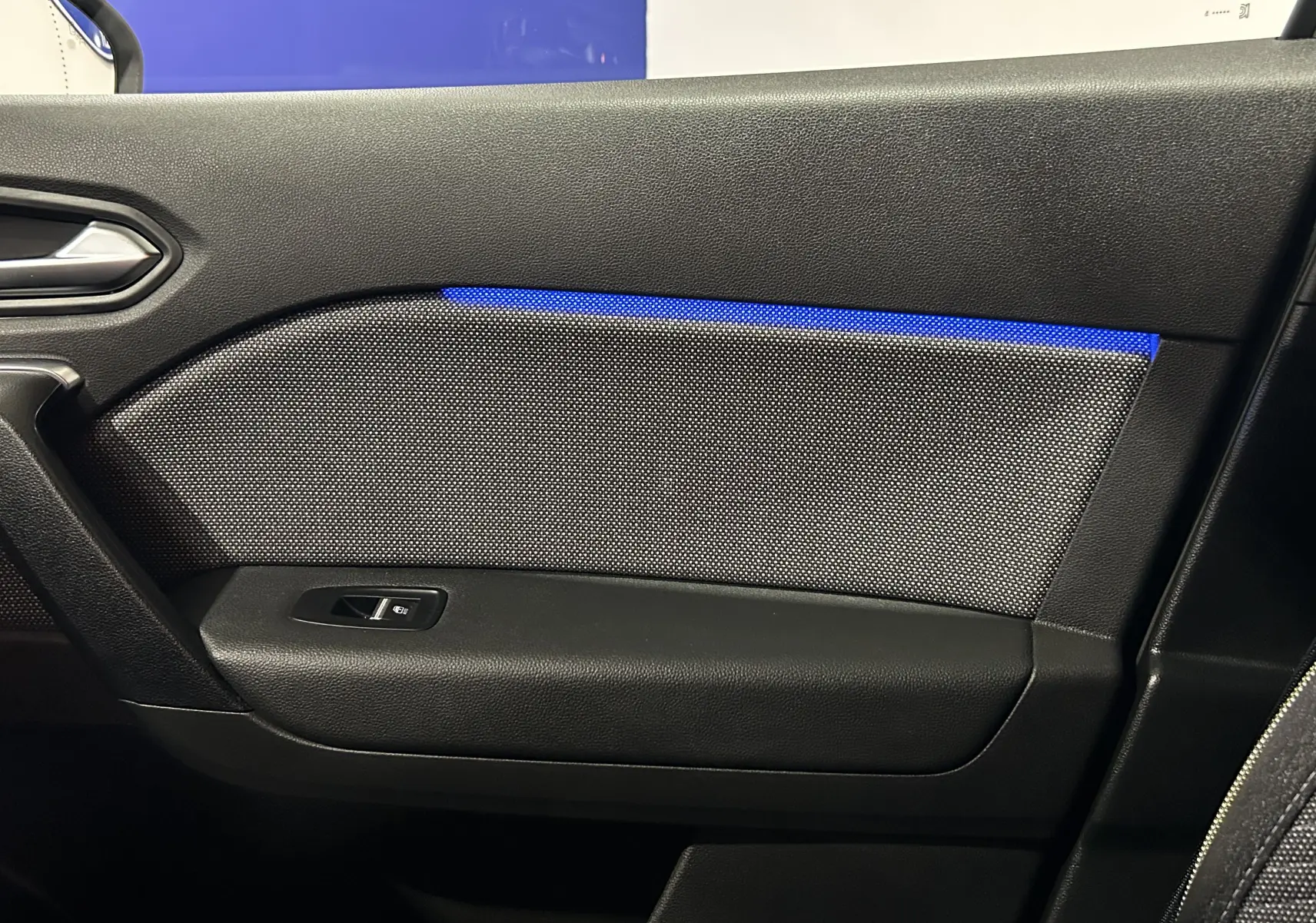 Détail de la porte intérieure côté droit du Renault Symbioz blanc nacré, avec éclairage d'ambiance bleu et bouton de fenêtre.