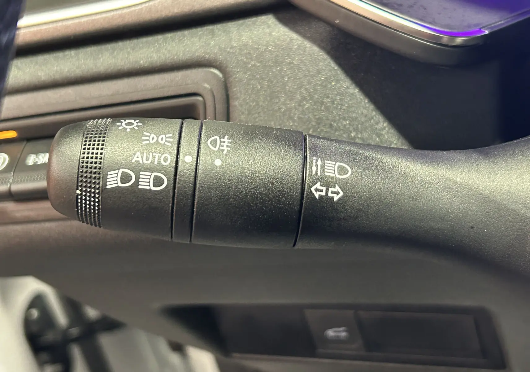 Gros plan sur la commande de phares et clignotants noire dans l'habitacle du Renault Symbioz blanc nacré 2025.