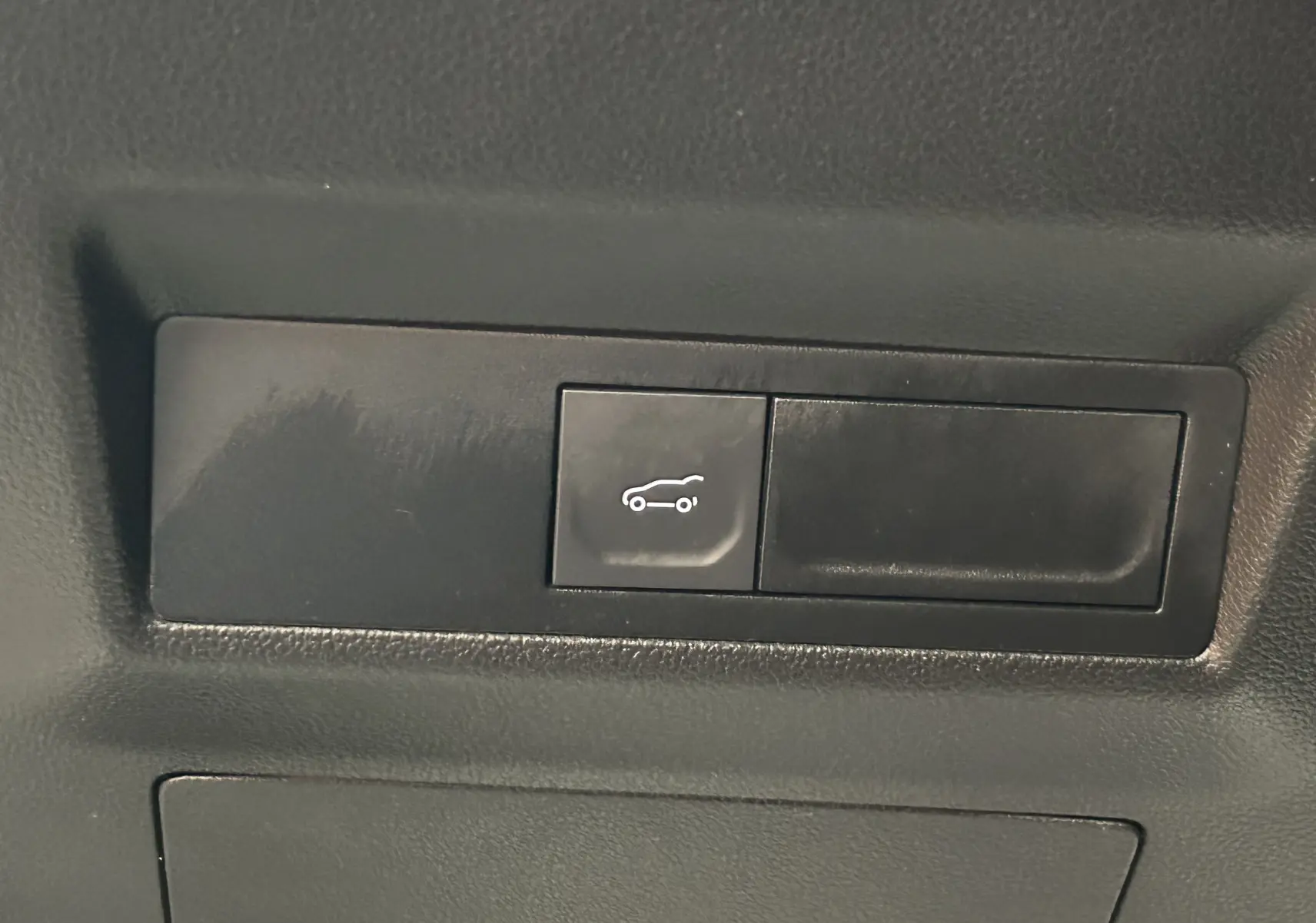 Bouton de hayon électrique noir avec pictogramme blanc dans l'habitacle d'une Renault Symbioz blanc nacré 2025 E-Tech Hybrid.