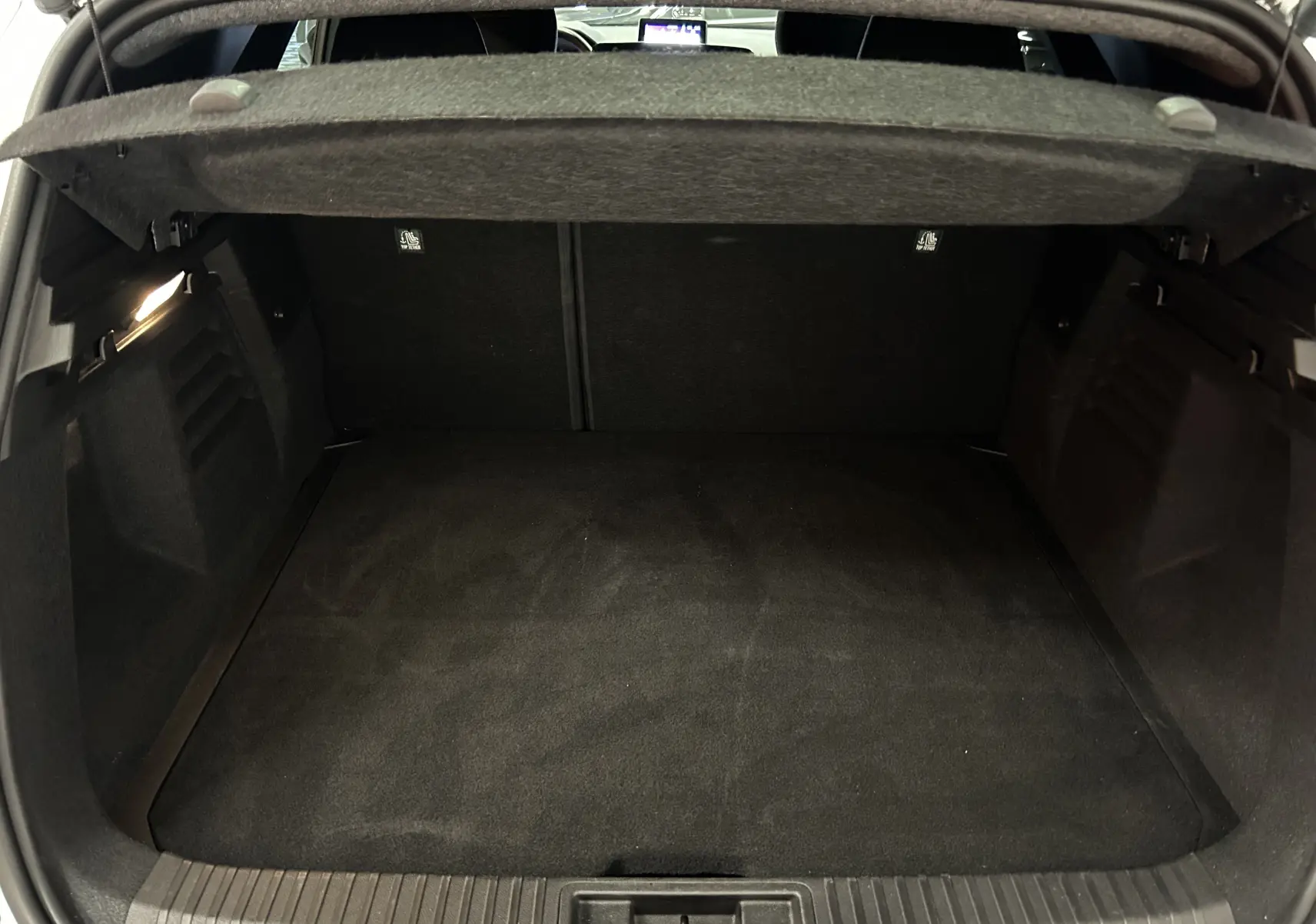 Coffre ouvert spacieux et propre du Renault Symbioz blanc nacré, vue intérieure arrière avec cache-bagages relevé.