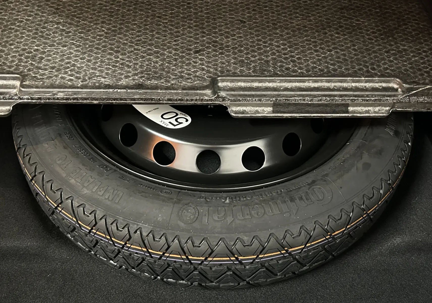 Gros plan sur la roue de secours noire dans le coffre du Renault Symbioz blanc nacré 2025.