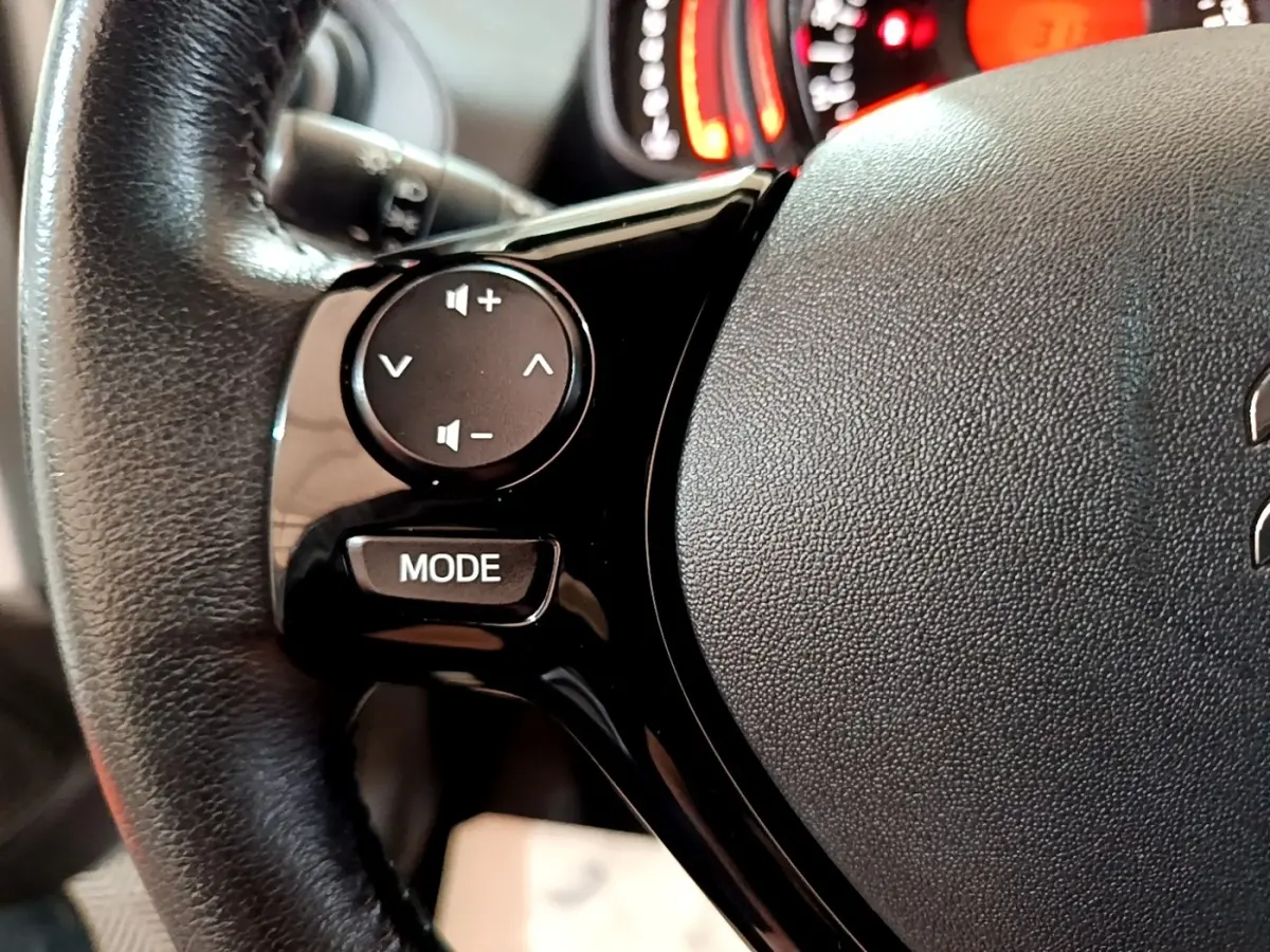 Gros plan sur les commandes du volant cuir noir de la Citroën C1 VTi 72 Shine, avec boutons de volume et mode.