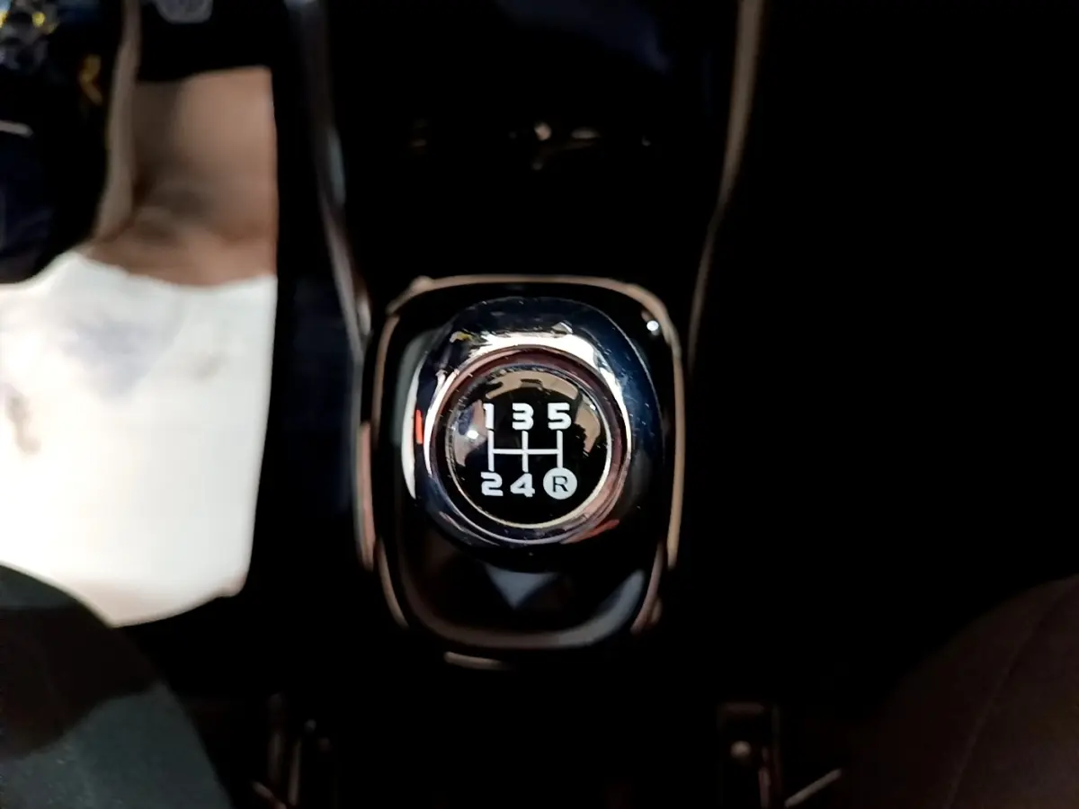 Gros plan sur le levier de vitesses manuel noir et chrome de la Citroën C1 Shine gris clair, intérieur sombre.