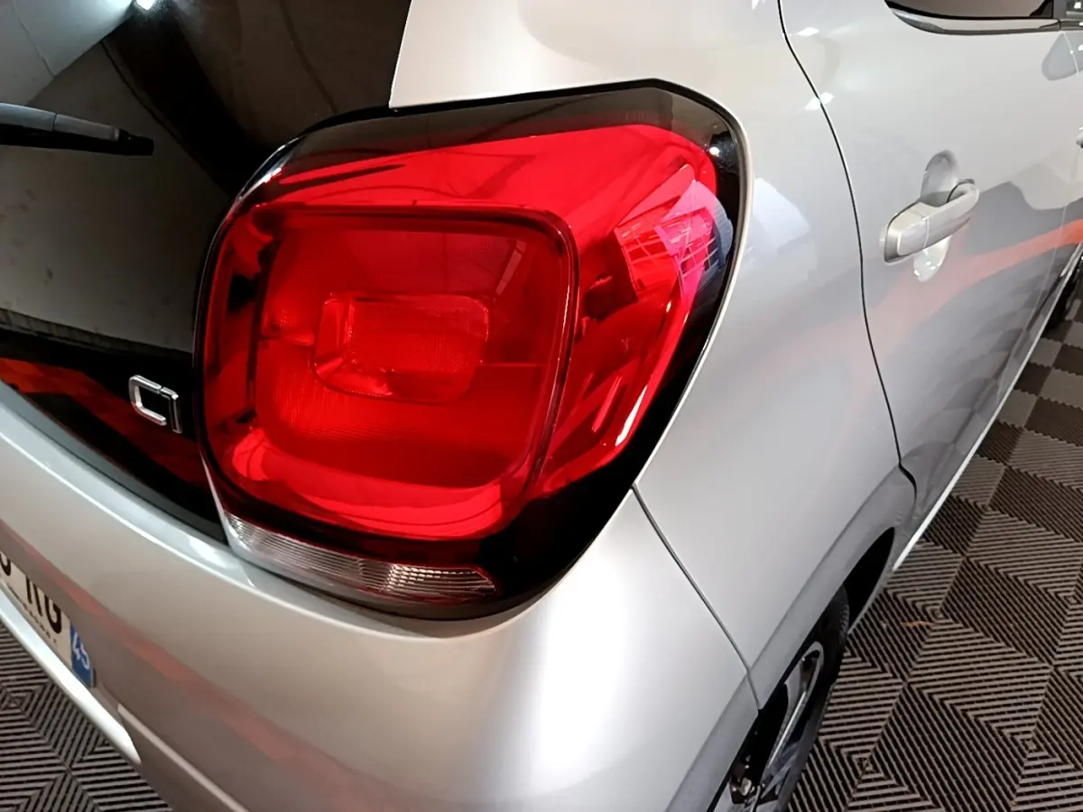 Gros plan sur le feu arrière droit rouge d'une Citroën C1 gris clair, vue trois quarts arrière droit.