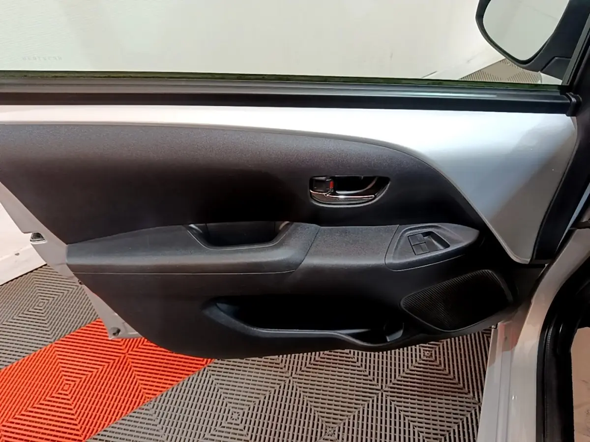 Vue intérieure de la porte avant gauche gris clair de la Citroën C1 avec commandes de vitres et poignée chromée.