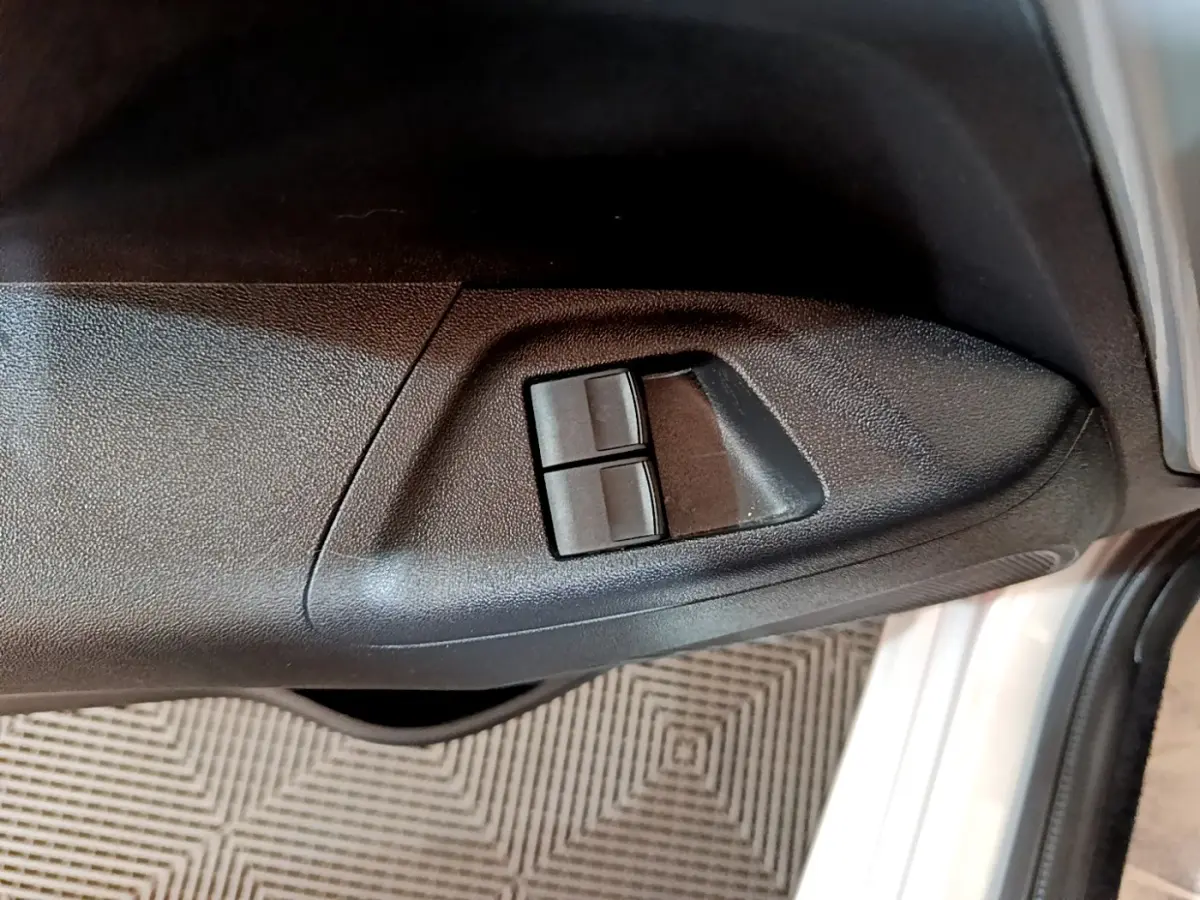 Gros plan sur les commandes de lève-vitres côté conducteur d’une Citroën C1 gris clair, porte ouverte.