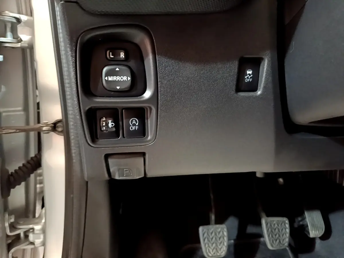 Vue intérieure côté gauche du tableau de bord gris clair d'une Citroën C1 avec commandes des rétroviseurs et pédales visibles.