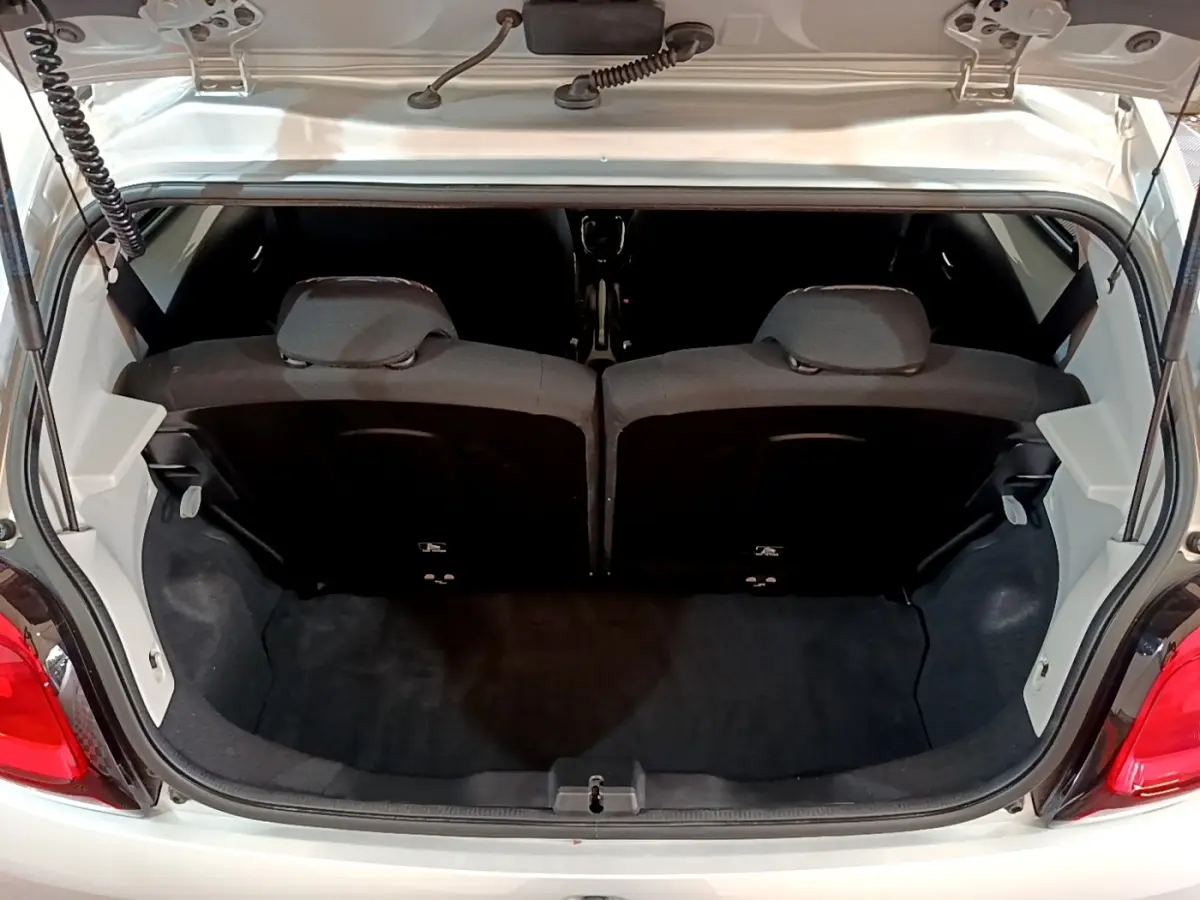 Coffre ouvert vu de l'arrière d'une Citroën C1 gris clair, montrant la banquette arrière et l'espace de chargement.
